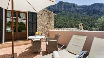 A terrace with wicker furniture, a stone wall, and a mountain view.