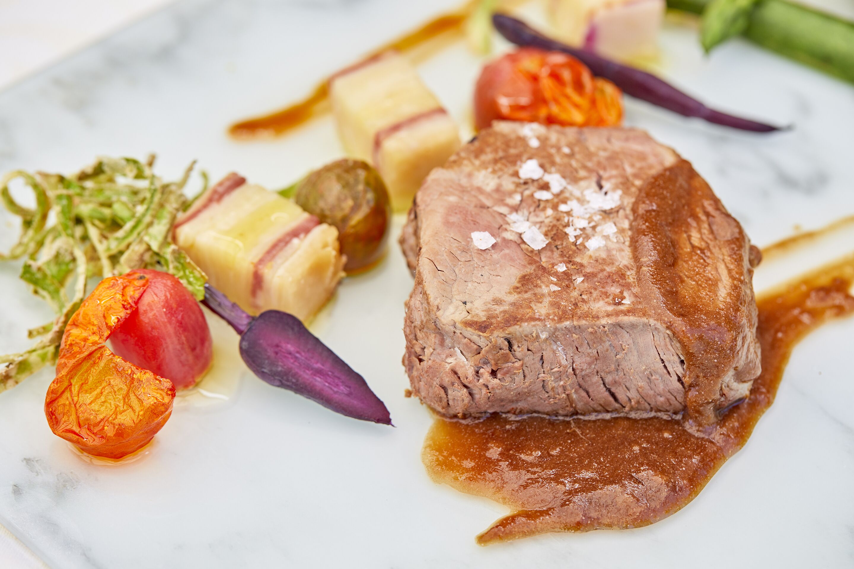 Un plato de comida con carne, verduras y salsa.