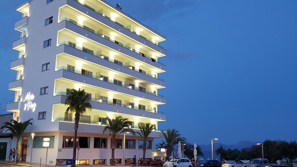 Een meerhoog hotel met verlichte balkons en een bord waarop staat dat het een hotel is.