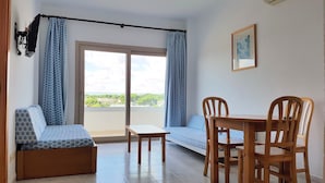 Een kamer met balkon, een bed, een tafel en stoelen.