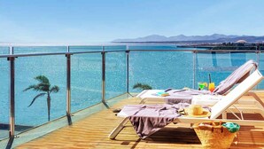 A balcony with two sun loungers, a wicker basket, and a drink on the table. - Arrecife Gran Hotel & Spa (Arrecife)