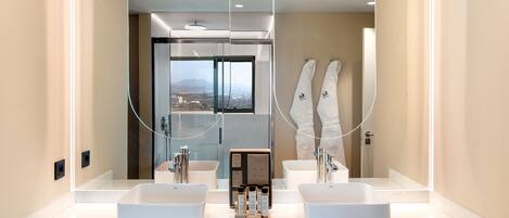 A modern bathroom with two sinks, a large mirror, and a view of the city through the window.