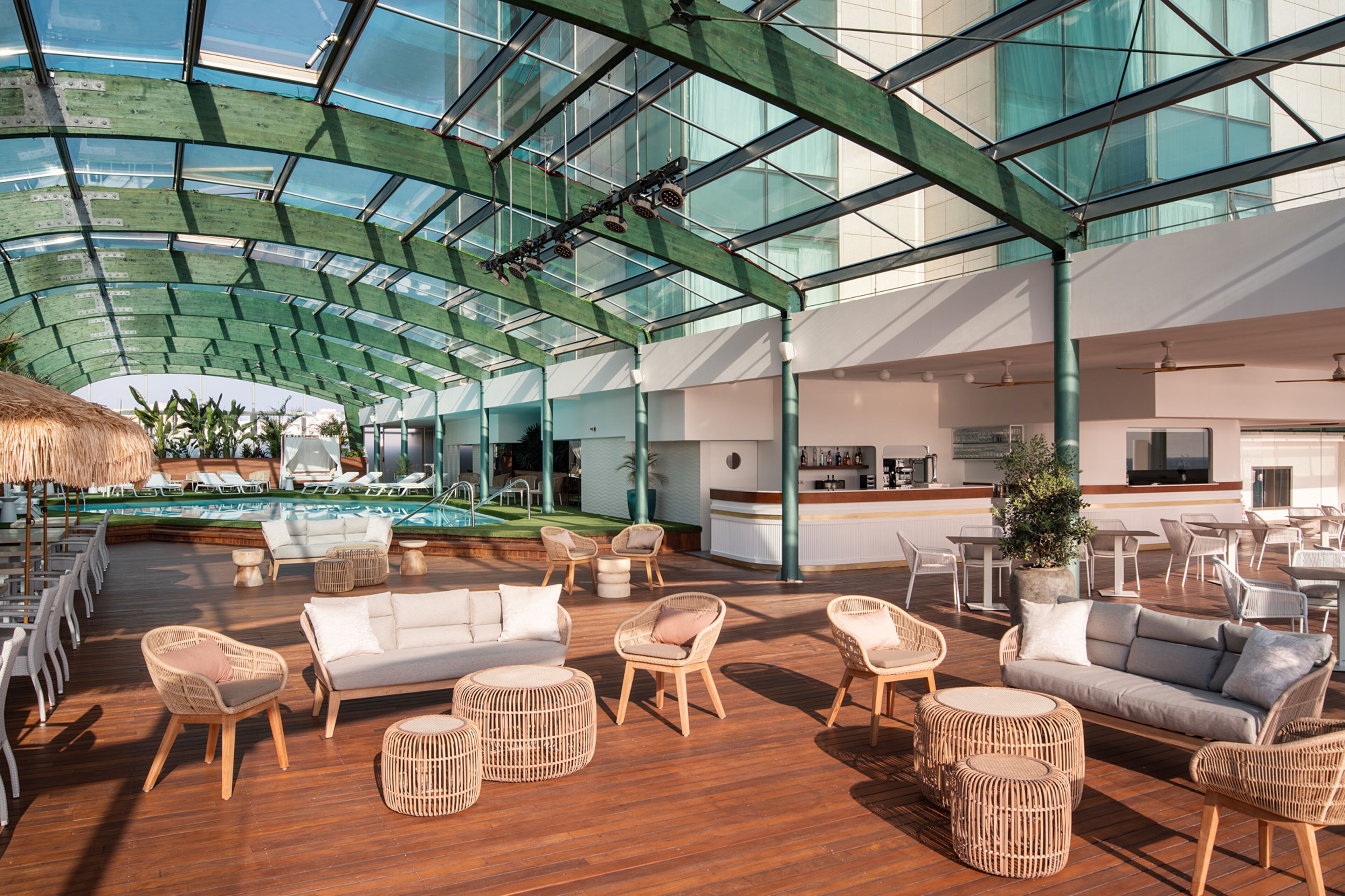 A spacious indoor area with a glass ceiling, a pool, and various seating arrangements.