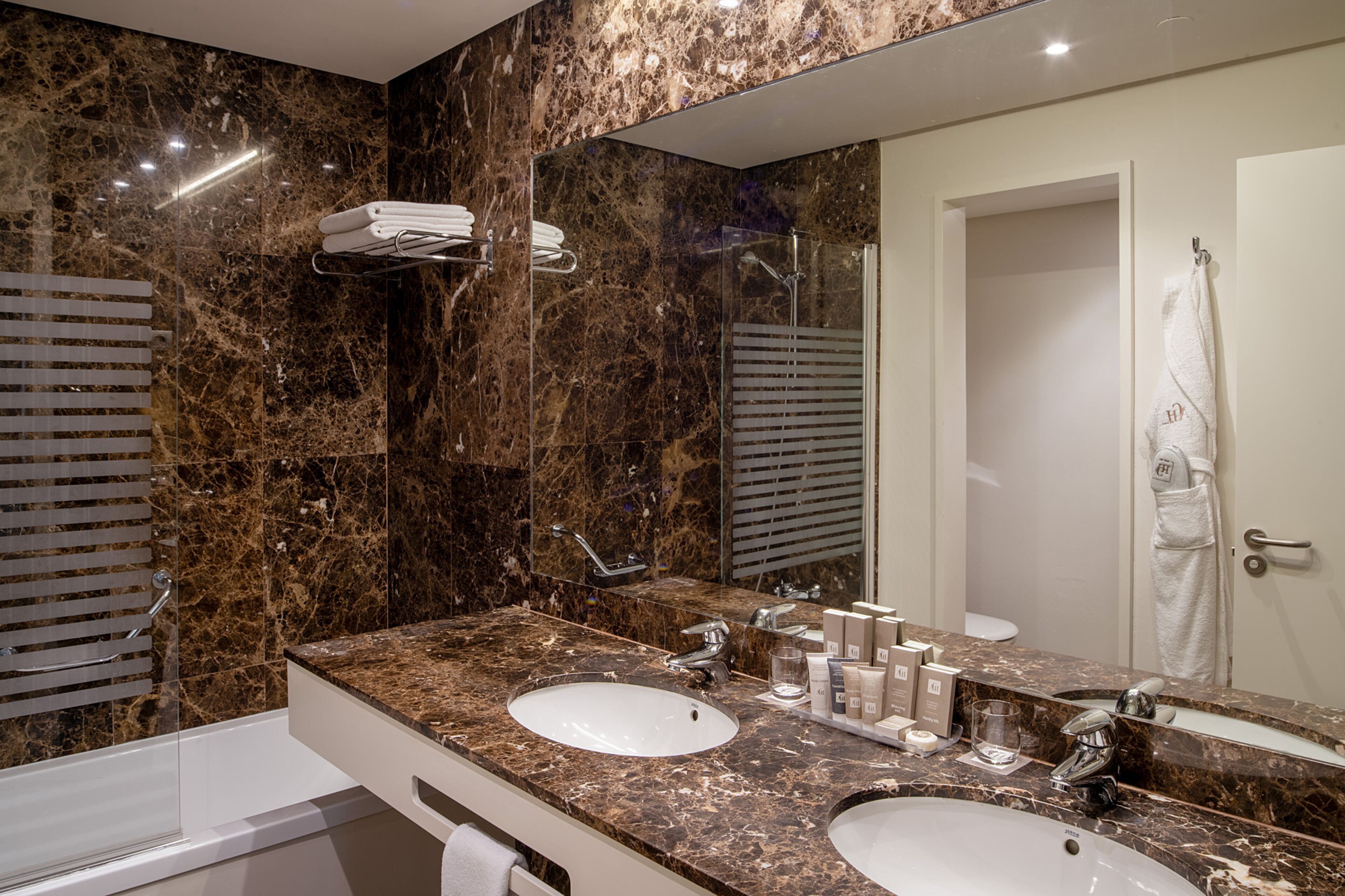 A bathroom with two sinks, a large mirror, and a towel rack.