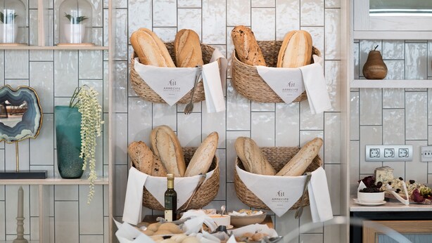 Four baskets of bread on a wall, each with a napkin and a logo. - Arrecife Gran Hotel & Spa (Arrecife)
