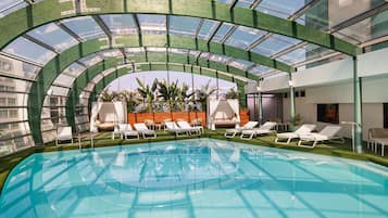 Alberca techada, sombrillas en la alberca y camastros