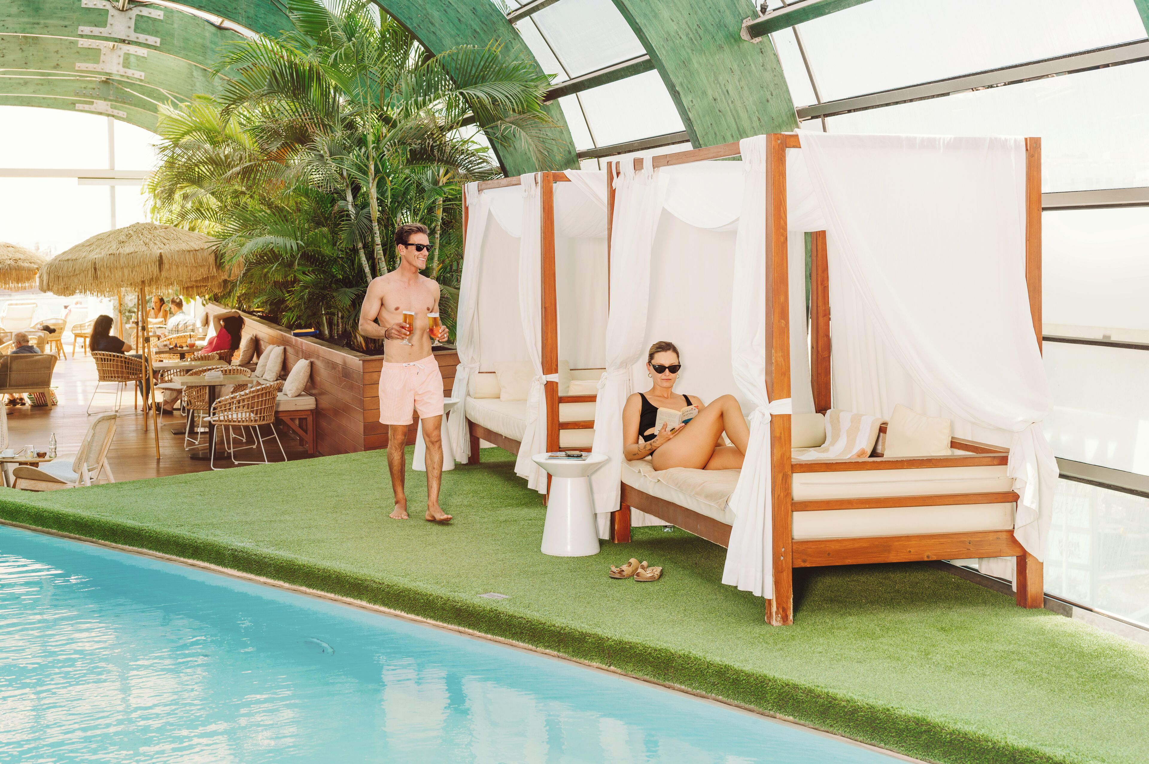 A poolside area with lounge chairs, a small table, and a pool.