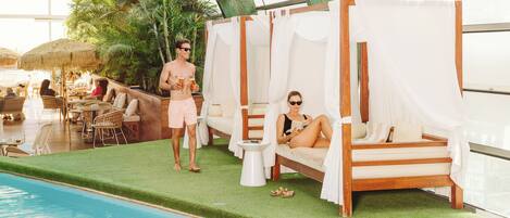 Un área junto a la piscina con sillones de descanso, una mesita y una piscina.