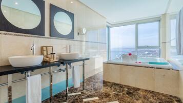 A modern bathroom with two sinks, a large mirror, and a bathtub with a view.