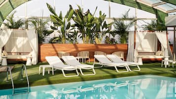 A pool area with lounge chairs, a wooden wall, and potted plants.