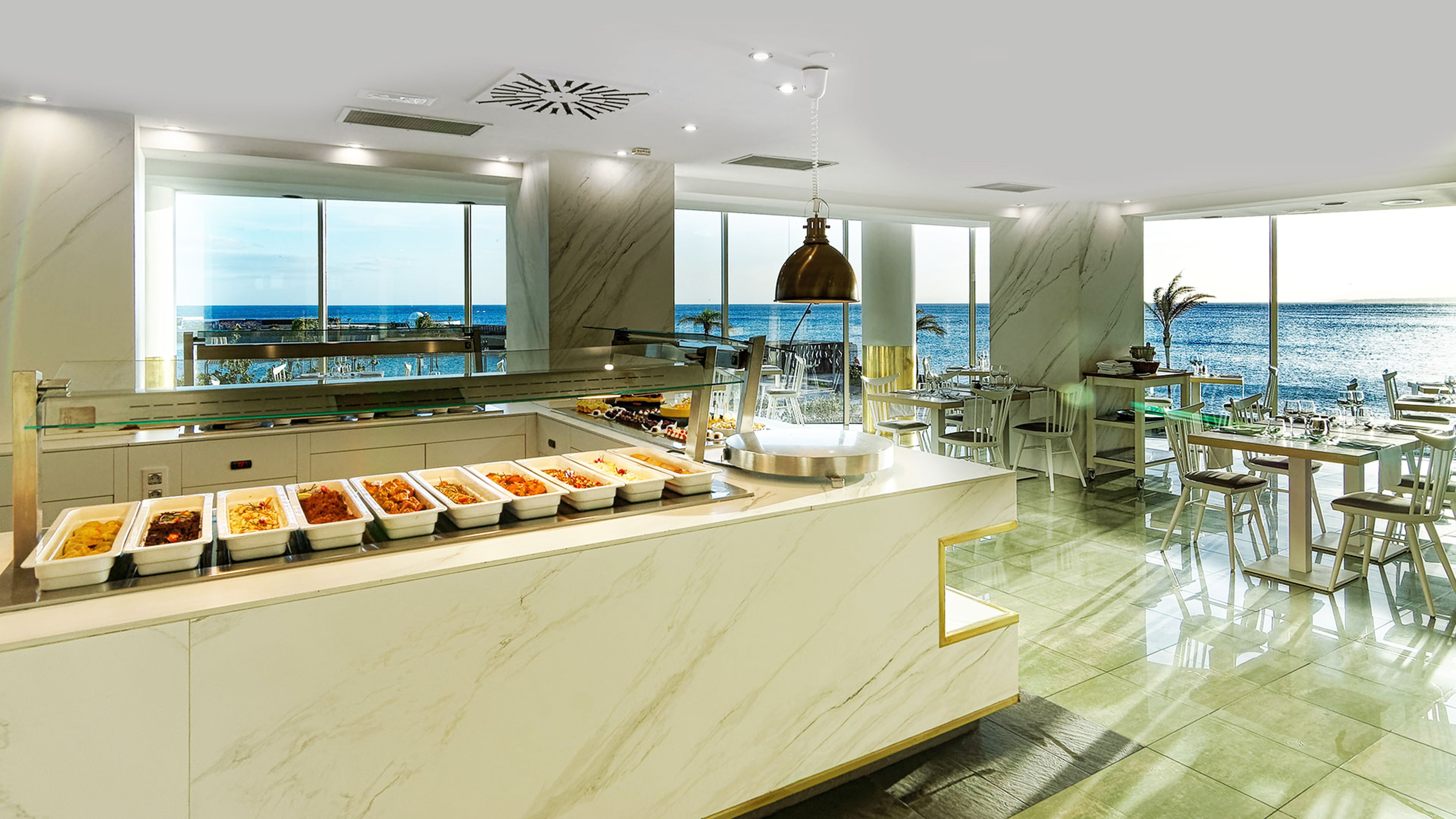 Cocina moderna con bufé, ventanas amplias y vista al océano.
