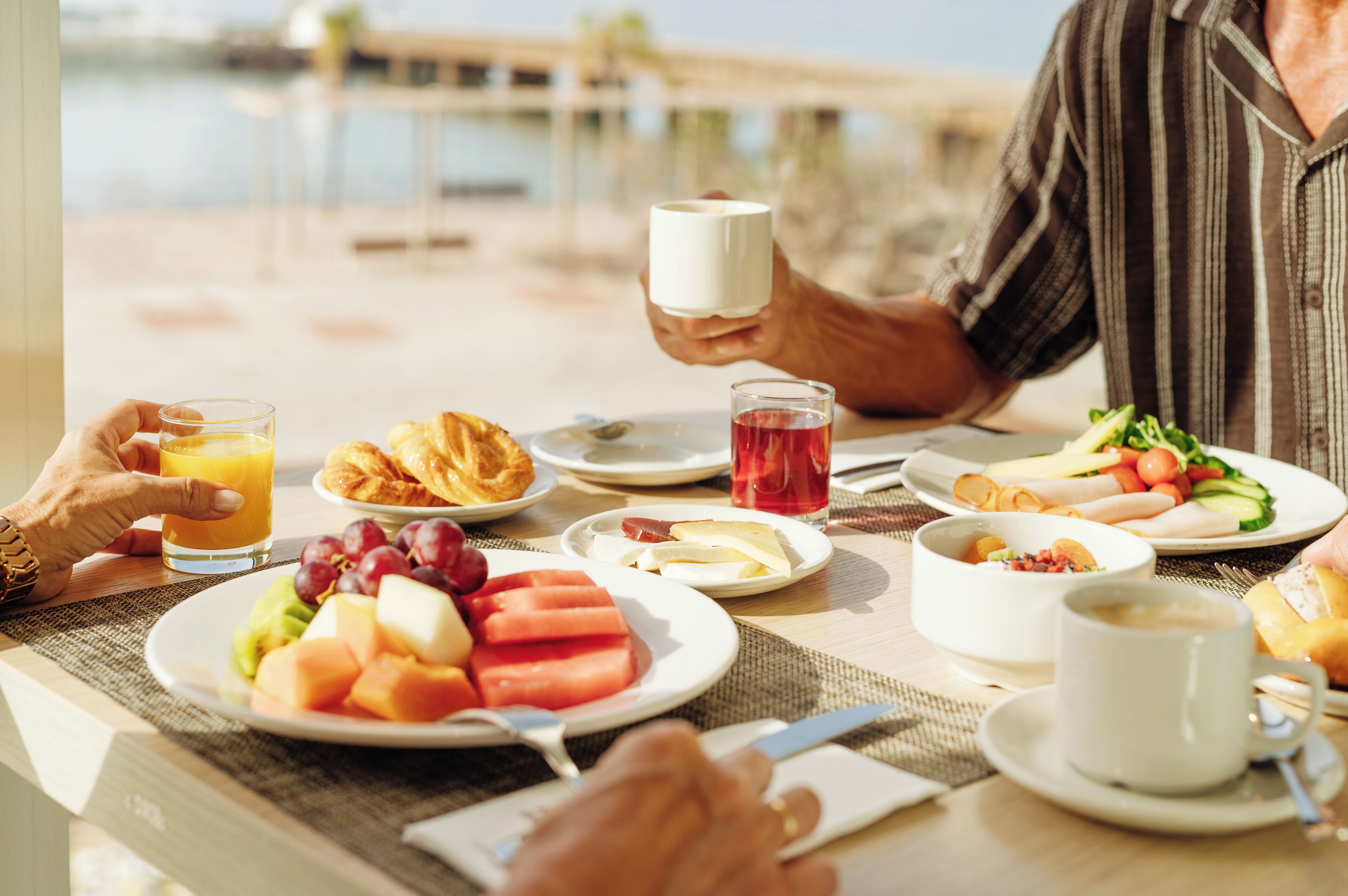 A breakfast table with various foods and drinks, including croissants, fruit, and coffee.
