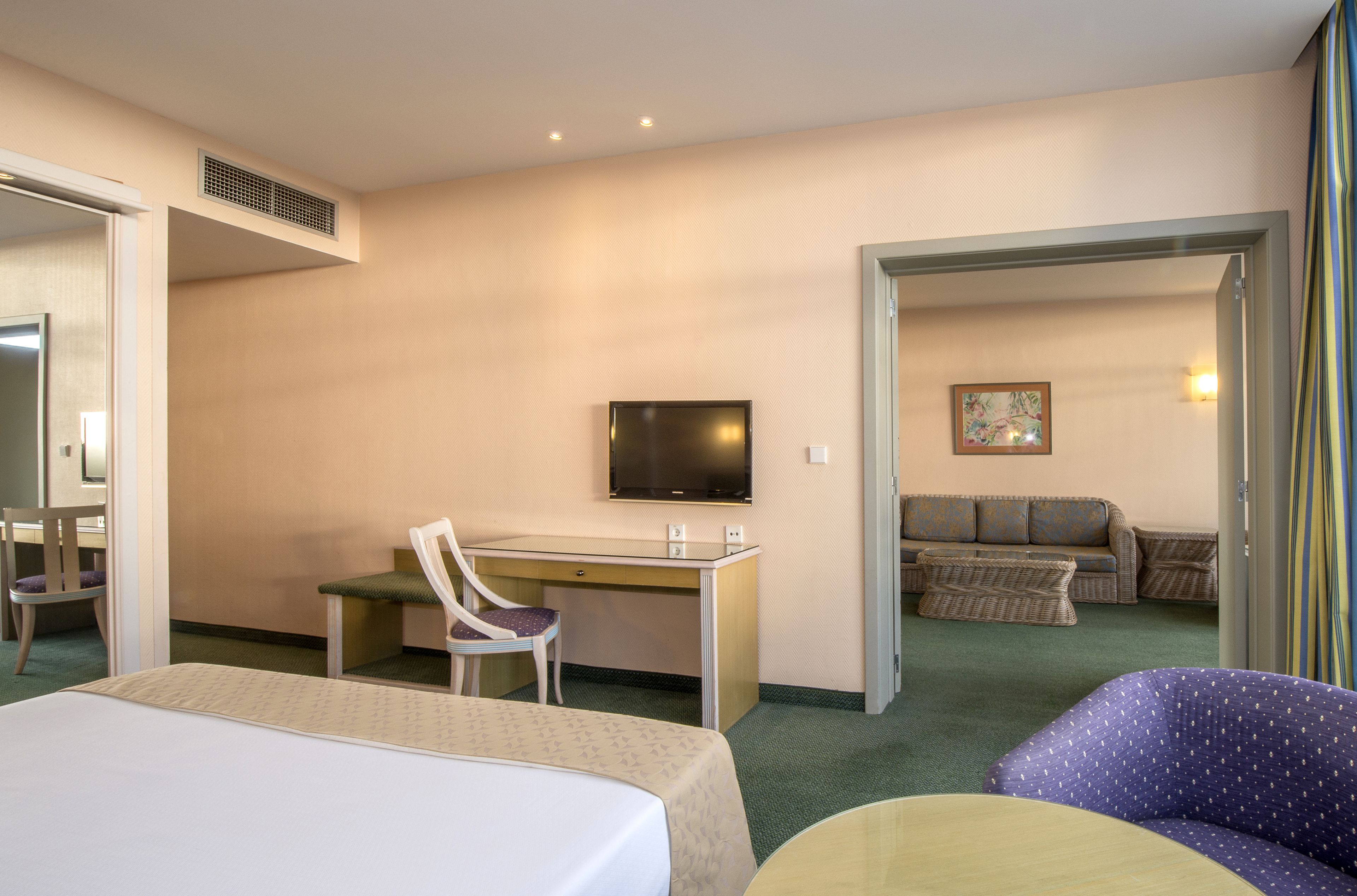 Una habitación de hotel con cama, escritorio, silla, televisor y sofá.