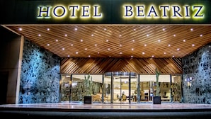 The exterior of Hotel Beatriz with a modern design, featuring a prominent entrance, a glass facade, and a wooden ceiling. - Hotel Beatriz Costa & Spa (Teguise)