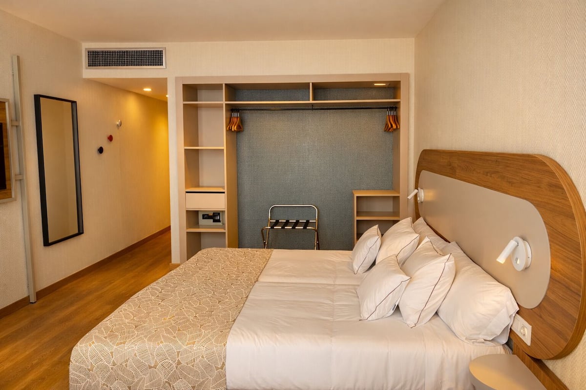 A bedroom with a bed, a wardrobe, a mirror, and a towel rack.