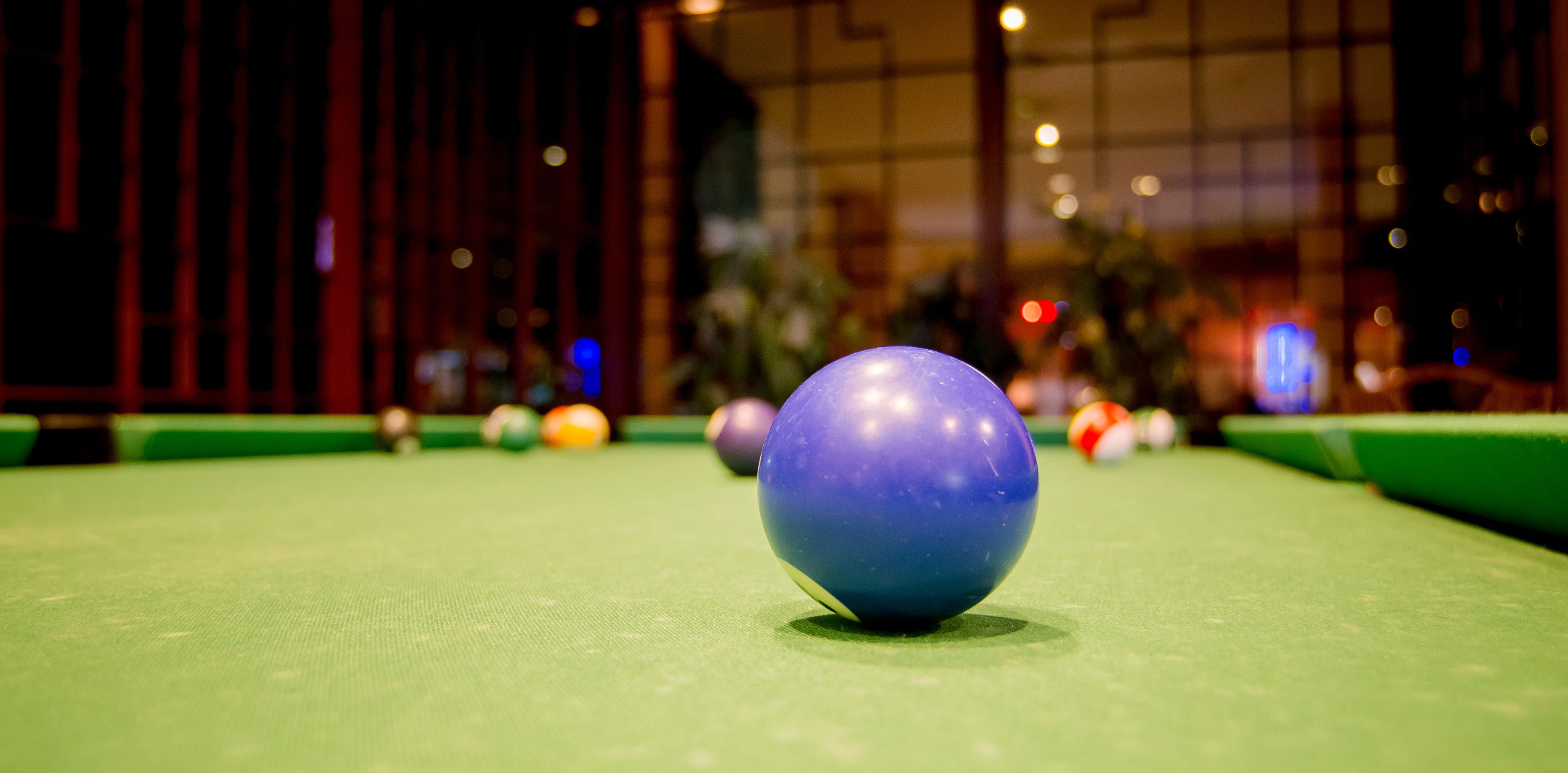 Gros plan d’une table de billard, avec une boule blanche au centre, mise en évidence, et d’autres boules de billard en arrière-plan.