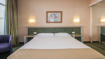 A hotel room with a large bed, two bedside tables, a chair, and a painting on the wall.
