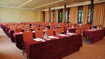 A conference room with rows of tables and chairs, equipped with water bottles and wine glasses.