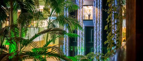A well-lit indoor garden with palm trees and decorative lights.