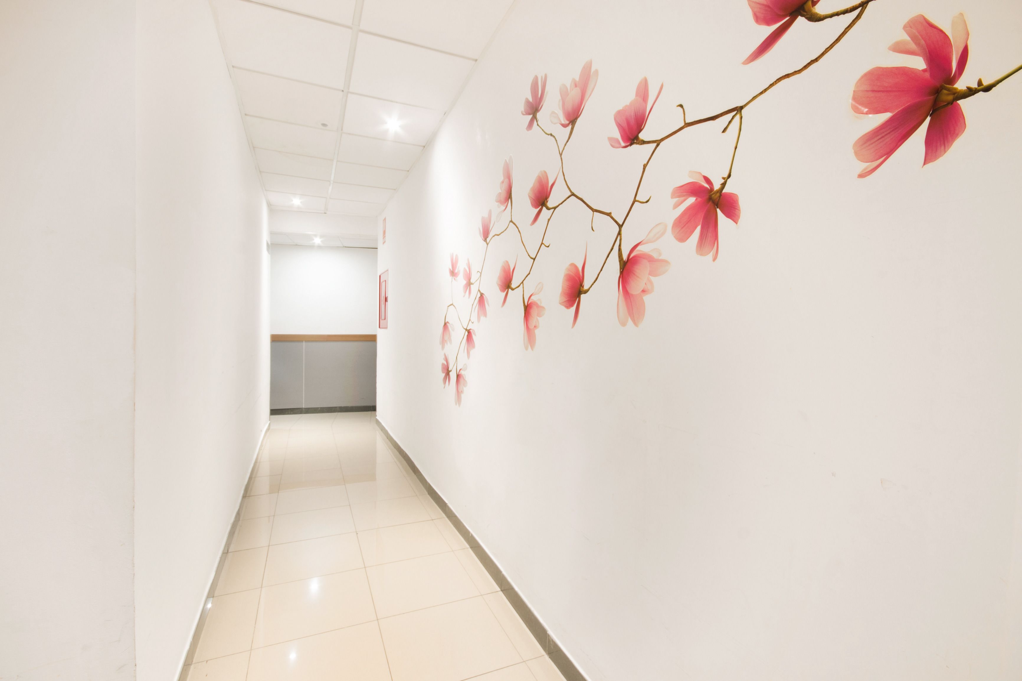Um corredor com piso ladrilhado e parede com mural floral.