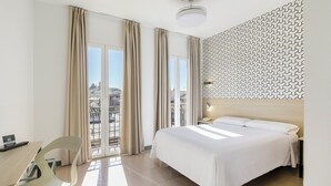 Habitación de hotel con cama, escritorio, silla, mesita de noche y pared con diseño.