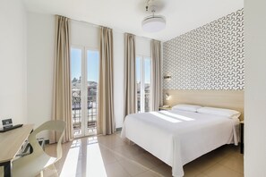 Habitación de hotel con cama, escritorio, silla, mesita de noche y pared con diseño.