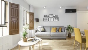 Una sala de estar moderna con un sofá gris, cojines amarillos, una mesa blanca y una planta en maceta.