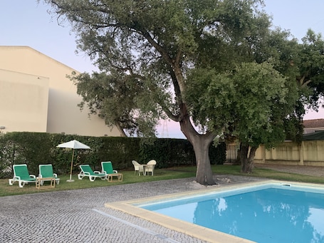 Una piscina al aire libre de temporada, sillones reclinables de piscina