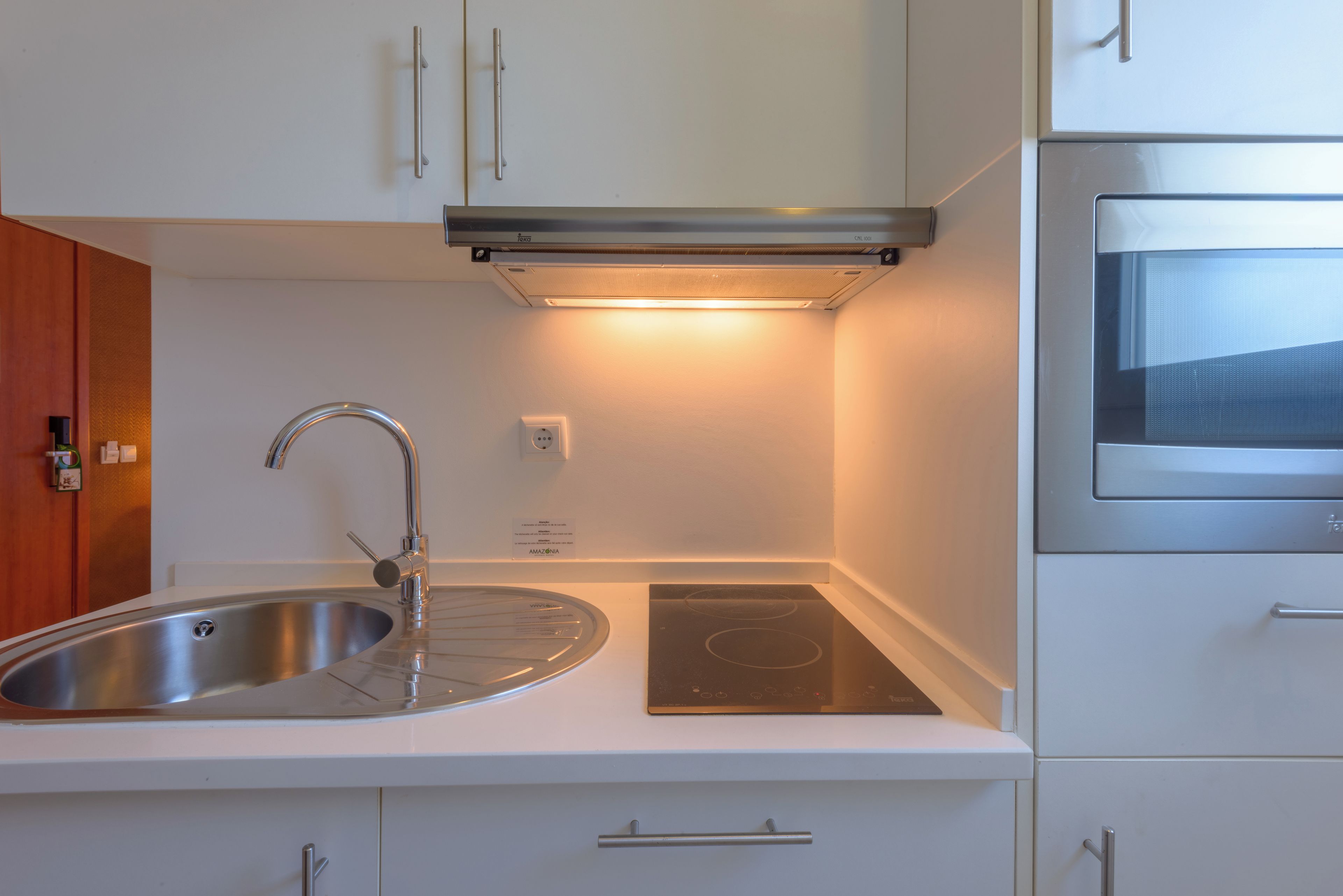 Una cuina moderna amb un rentaplat de thép inoxidable, una placa vitroceràmica i un forn encastat.
