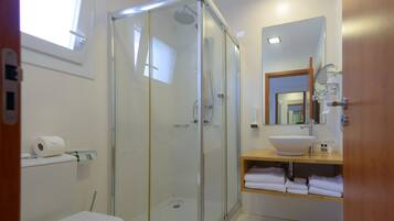 A modern bathroom with a glass-enclosed shower, a white sink, and a mirror above the sink.