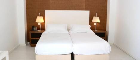 A double bed with white bedding, two bedside tables with lamps, and a wooden headboard.