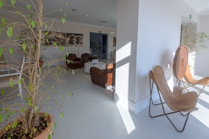 Un interior moderno con una planta en maceta, sillas de cuero y una escalera al fondo.
