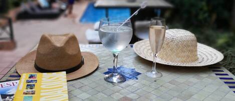 A table with a hat, a book, a glass of water, and a straw drink.