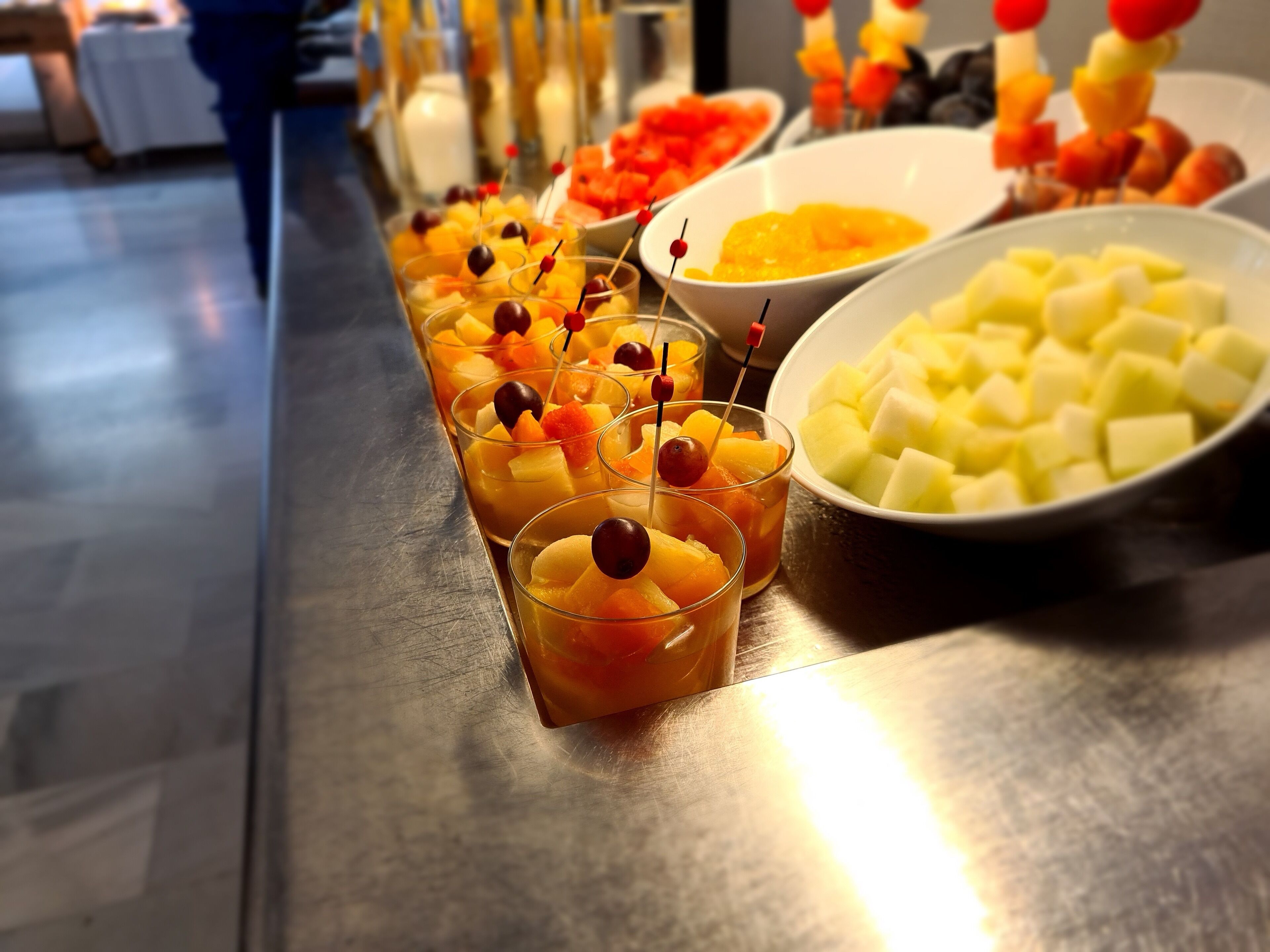 A buffet table with various fruit options and a bowl of cubed cheese.