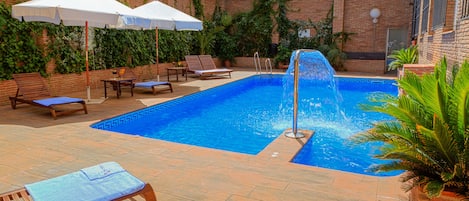 Alberca al aire libre por temporada y sombrillas en la alberca