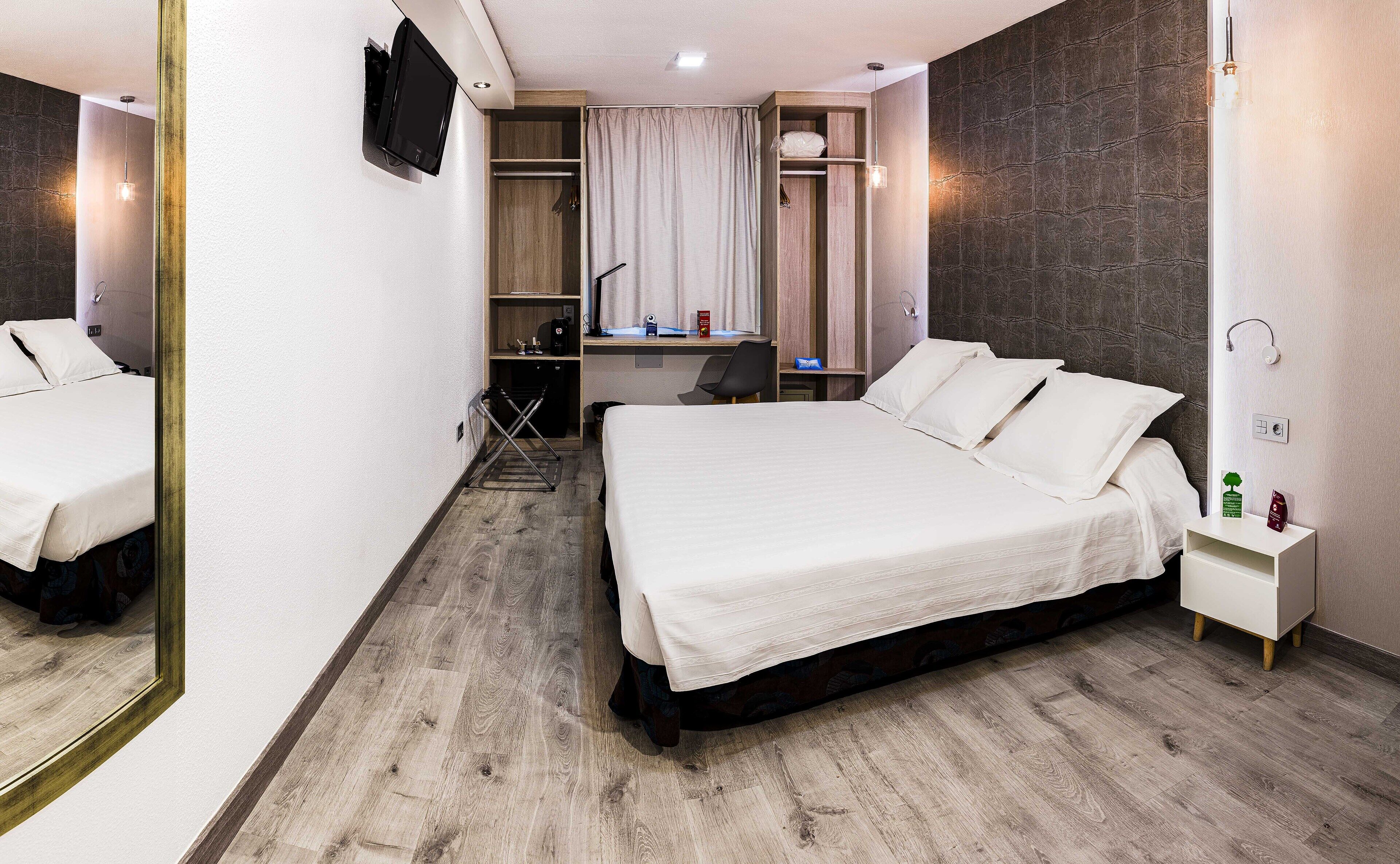 Habitació d'hotel amb un llit gran, una taula i una cadira.