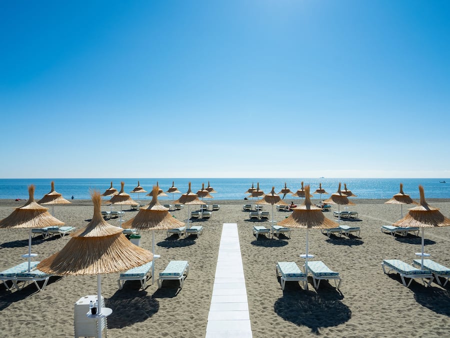 Na praia, espreguiçadeiras, guarda-sóis, toalhas de praia