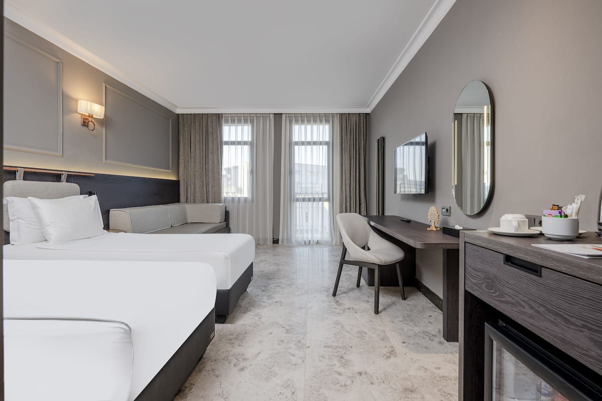 Ein Hotelzimmer mit Bett, Schreibtisch, Sessel, Fernseher und Spiegel.