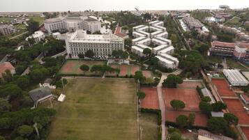 An aerial view of a large hotel complex with multiple buildings, tennis courts, and surrounding greenery.
