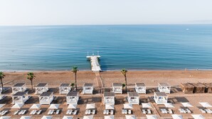 A beach with rows of white beach huts, a pier extending into the sea, and a clear blue sky. - ADORA HOTEL & RESORT - All inclusive (Serik)