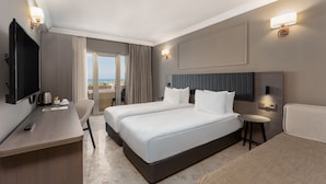A hotel room with two beds, a desk with a TV, and a view of the outdoors. - ADORA HOTEL & RESORT - All inclusive (Serik)