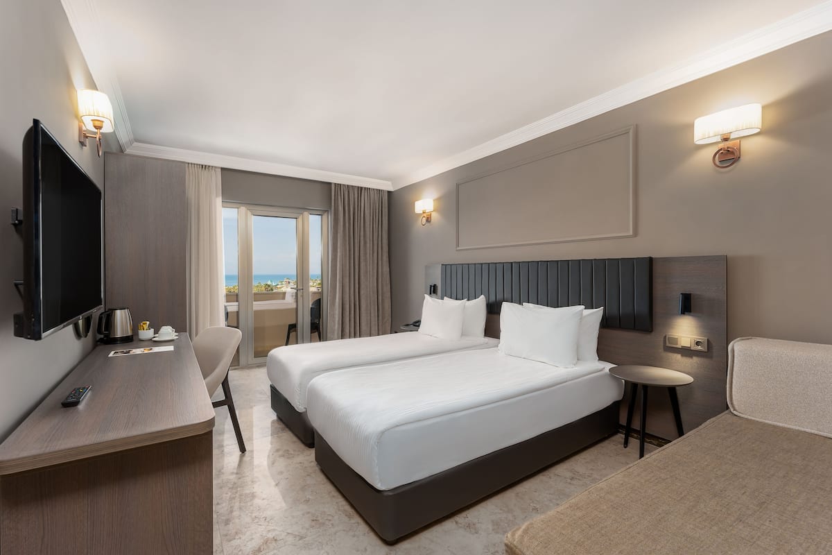 Ein Hotelzimmer mit zwei Betten, einem Schreibtisch mit Fernseher und Blick ins Freie.