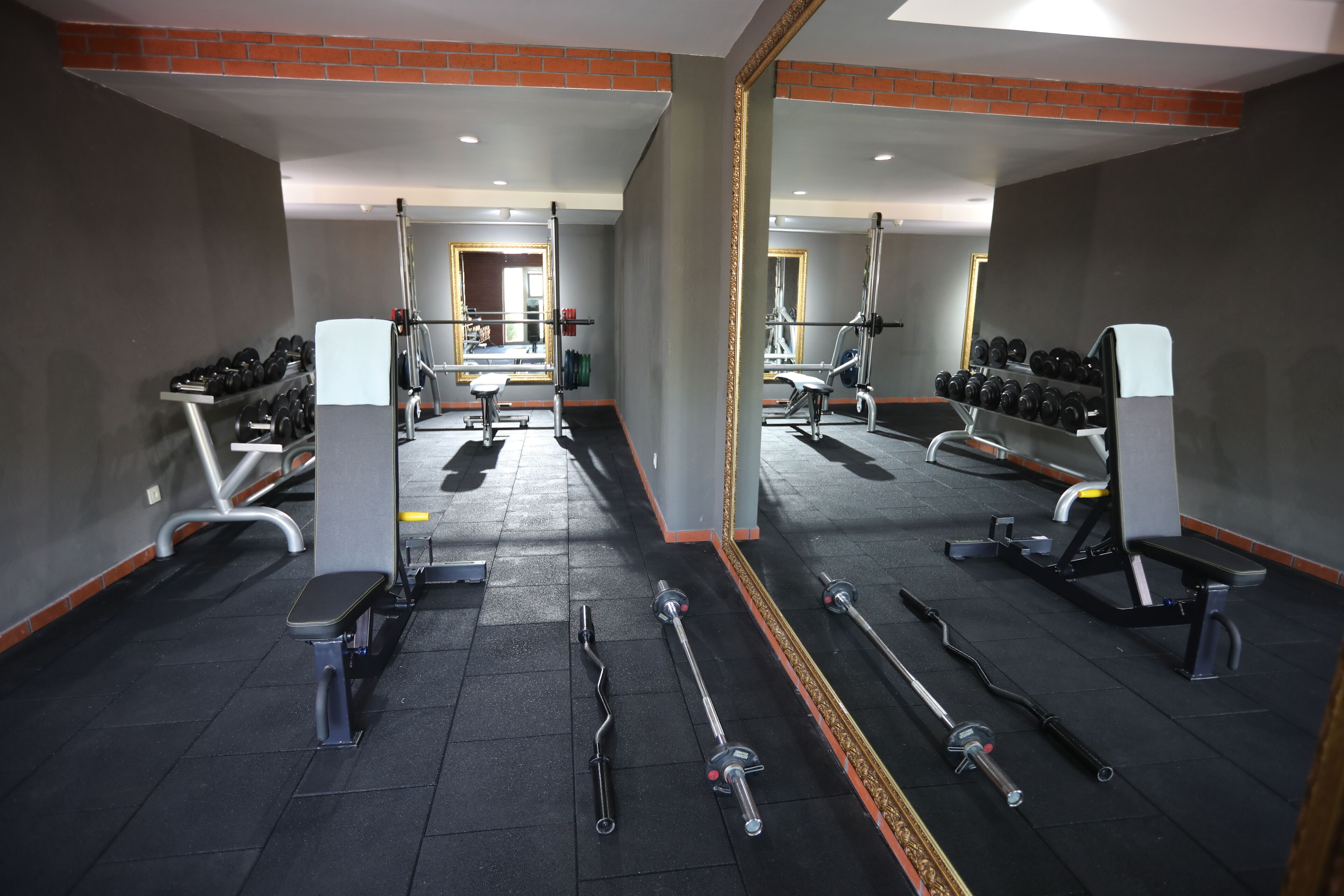 A gym with various exercise equipment, including dumbbells, benches, and weight machines.