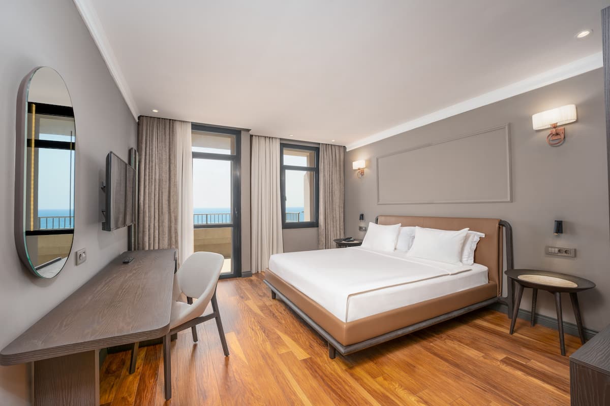 Ein modernes Hotelzimmer mit einem großen Bett, einem Schreibtisch, einem Sessel und einem Fernseher.