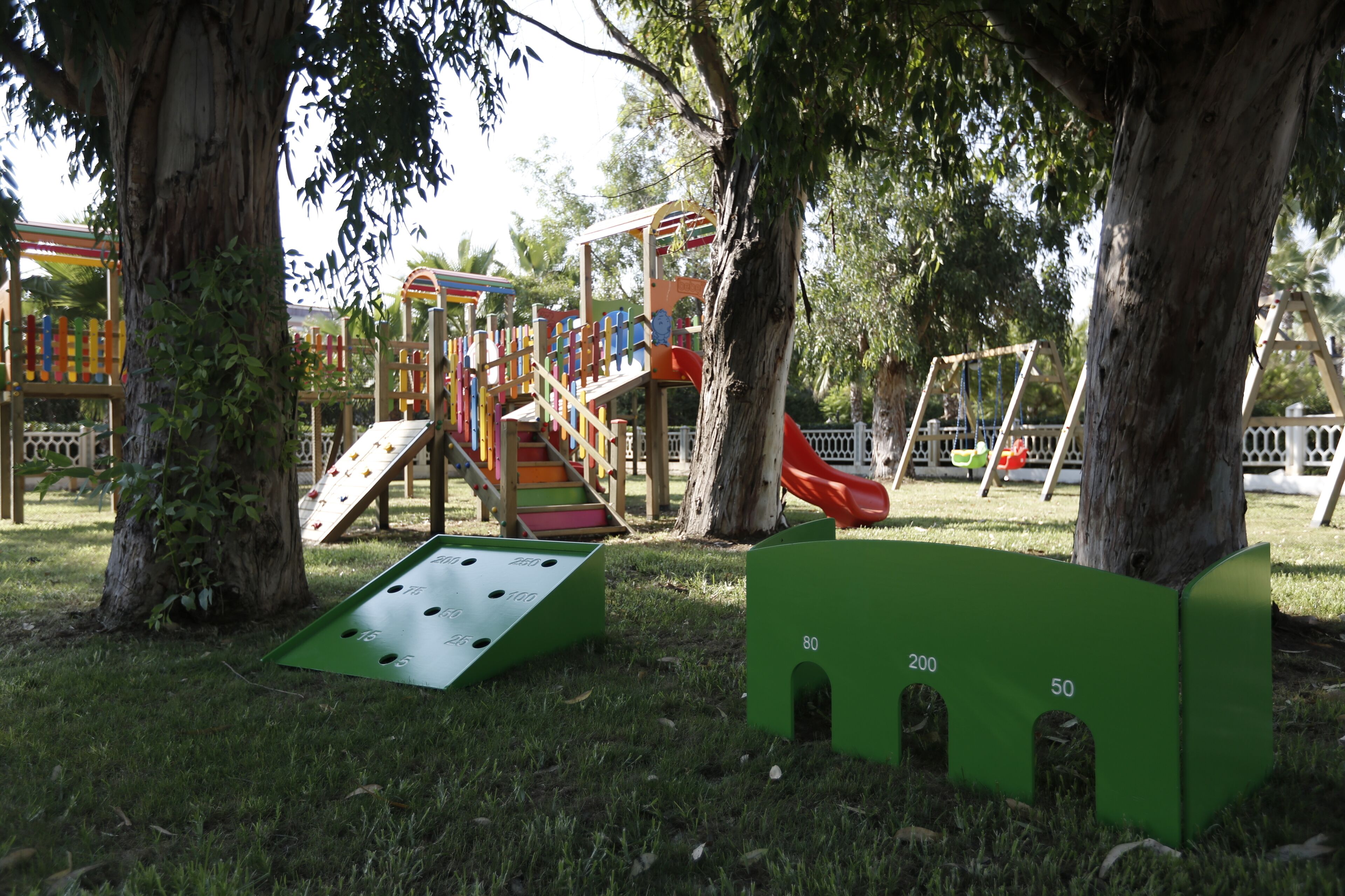 Un parque infantil con toboganes y estructuras para escalar, rodeado de árboles.