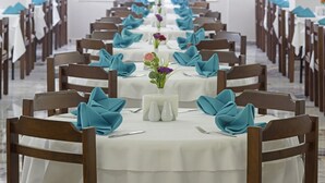 Une longue table à manger, avec des serviettes bleues, des nappes blanches et de petits vases ornés de fleurs.