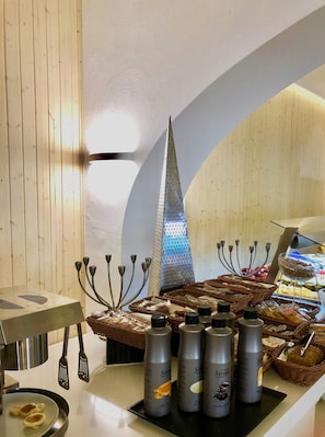 Una mesa de buffet con diferentes alimentos, incluyendo pan y bollería, y varias botellas de sirope.