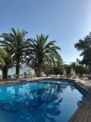 Una piscina al aire libre de temporada, sombrillas, tumbonas