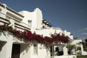 Un edificio blanco con balcón, puerta y ventana.