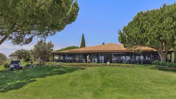 A building with a tiled roof, surrounded by trees and a grassy area.